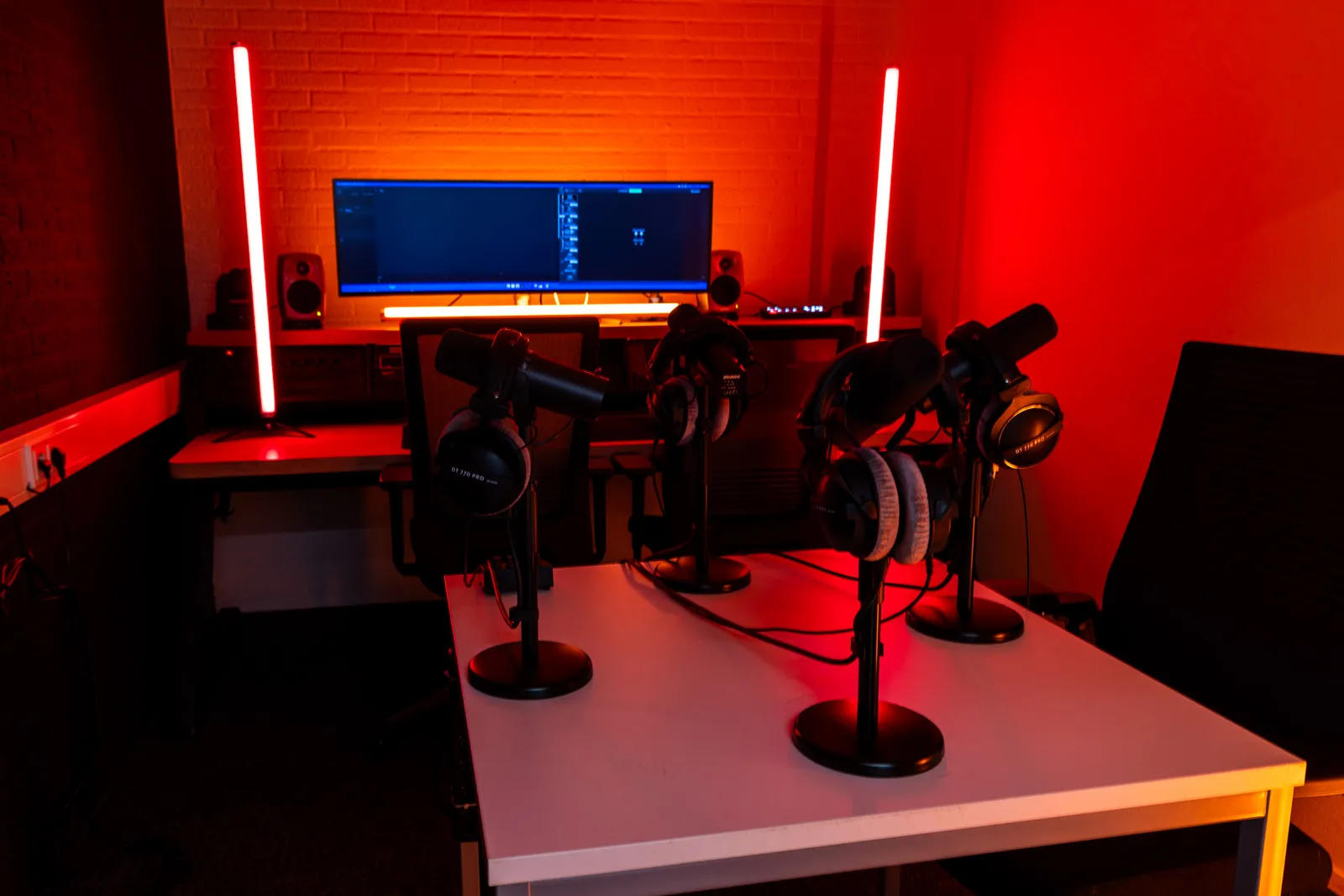 Podcast edit bay with four microphone stands, red lighting
