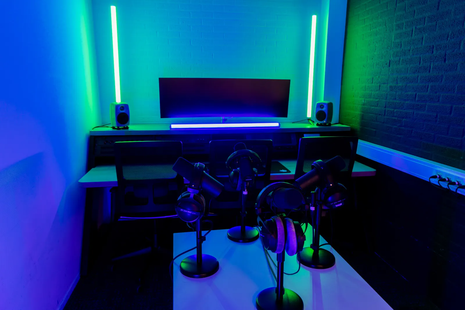 Podcast edit bay table with four microphone stands, teal lighting